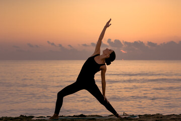  young girl practicing yoga at the beach at sunrise