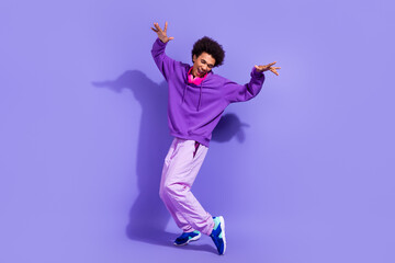 Fototapeta na wymiar Full length photo of satisfied pleasant guy dressed violet hoodie stylish sportswear dancing fooling isolated on purple color background