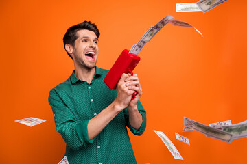 Photo of cheerful positive guy wear green shirt shooting money fan isolated orange color background