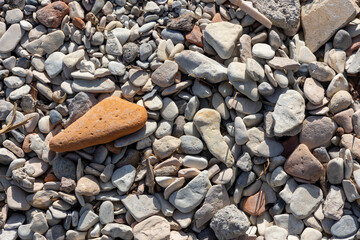 pebbles on a beach where a red one stands out - 664003520