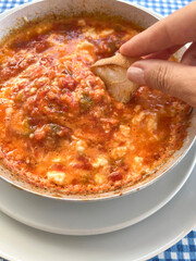 dipping bread slice into delicious scrambled eggs known as menemen in Turkish