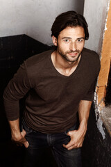 Fototapeta premium Portrait, fashion and confidence of man in home, apartment or rustic house. Style, casual and handsome, rugged and attractive person in jeans, trendy clothes or standing with hands in pocket in Spain