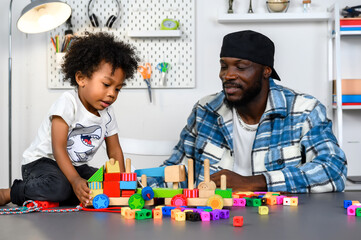 Fototapeta premium Loving Father Teaches and Plays with Little Son at Home for Skill Development with Wooden Toy and Color Cube. Father Nurtures Child's Skills Through Play and Education Concept.