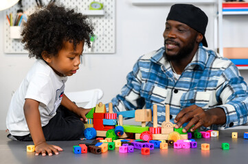 Fototapeta premium Loving Father Teaches and Plays with Little Son at Home for Skill Development with Wooden Toy and Color Cube. Father Nurtures Child's Skills Through Play and Education Concept.
