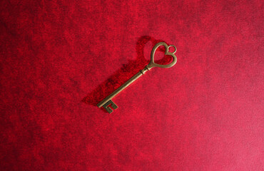 Vintage gold key with heart shaped top on red textured background