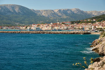 Cityscape of Baska on the island of Krk in Croatia. The old town with a promenade by the port. A tourist resort located on the Adriatic Sea with mountains in the background