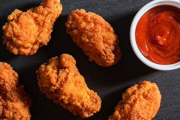Fried chicken strips breaded with ketchup on the table. View from above