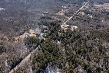 Aerial view of a house in Midland, Ontario, nestled among barren trees during winter. The property stands out against the snowy terrain, showcasing Canadian winter landscapes.