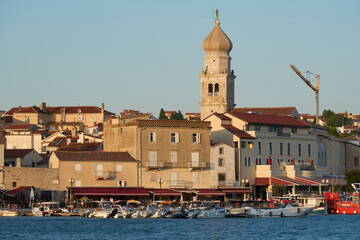 View of the harbor and the old town of Krk in Croatia during the golden hour before sunset.