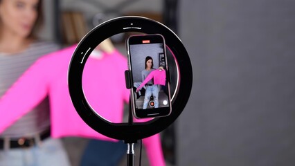 Display of mobile phone screen recording video blog. Female blogger holding and showing pink jumper...