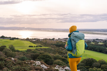 Fototapeta premium Traveler woman with her backpack admiring the landscape of Dublin Bay, Ireland
