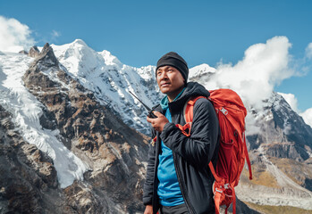 Portrait of Sherpa man with backpack using walkie-talkie for calling rescue helicopter with Mera...