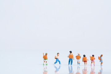 schoolchildren with schoolbags on white background, miniature figures scene, copy space