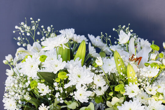 Bouquet of white flowers with green leaves on a dark background
