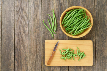Whole and chopped green beans on a cutting board with copy space for text, top view.