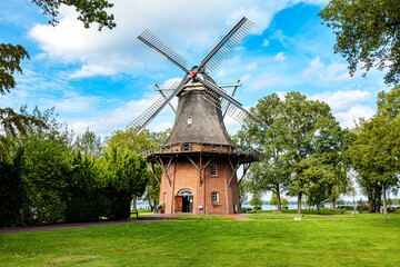 Old windmill in spa park with big tree, Bad Zwischenahn, Lower Saxony, Germany - obrazy, fototapety, plakaty