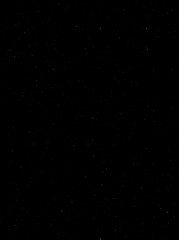 Festive vector background with gold glitter and confetti for christmas celebration. Black background with glowing golden particles.