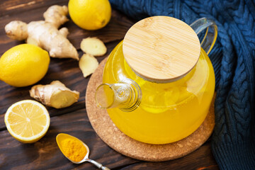 Healthy turmeric hot drink tea with lemon, ginger and honey on rustic table. Alternative medicine...