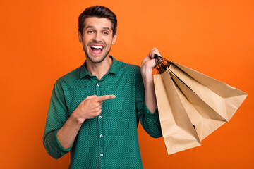 Photo of surprised businessman shopaholic black friday cheap packages direct finger eco friendly bags isolated on orange color background
