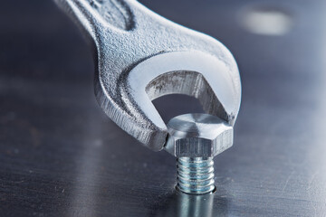 Wrench tightens bolt in steel billet. Spanner, bolt, screw and nuts. © evkaz