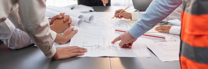 Engineer partner drawing and working on blueprint design together on office table for architectural...