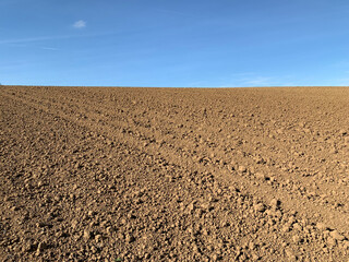 Only sky and earth on the horizon. A plowed field against a blue sky in sunny weather in Germany....