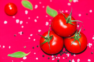 Fresh, red cherry tomatoes with green stems on red bckground