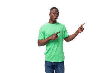 A 30-year-old African man dressed in a light green t-shirt points his hand at an advertisement