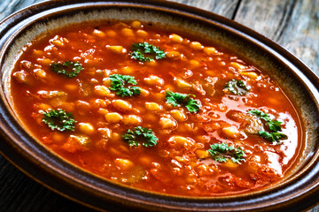 Moroccan cuisine - harira fresh vegetable soup with chickpeas and lentil on wooden table
