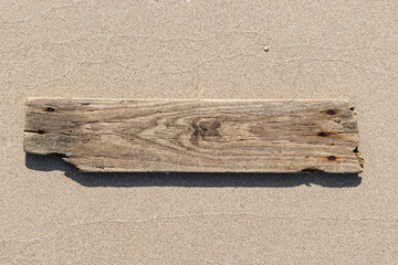 Sea drift wood plank isolated on beach sand background. Template mockup - obrazy, fototapety, plakaty