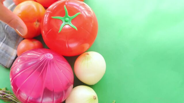 Hand taking vegetables and plastic vegetable shape storage containers from table