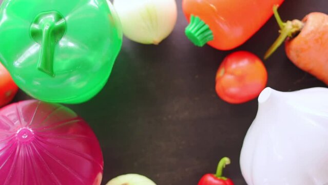 Hand taking vegetables and plastic vegetable shape storage containers from table