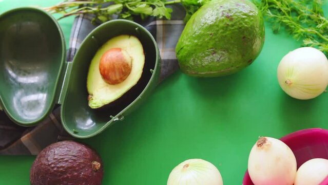 Hand taking avocado from plastic storage on green background