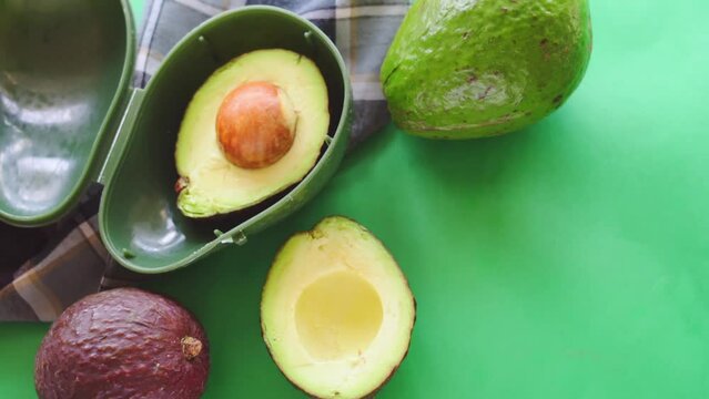 Hand taking avocado from plastic storage on green background