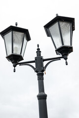 Fototapeta na wymiar street lamppost with four lighting fixtures against the sky