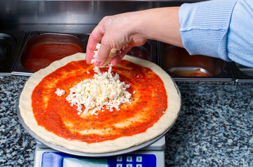 pizza base, chef pouring grated cheese on kitchen scale