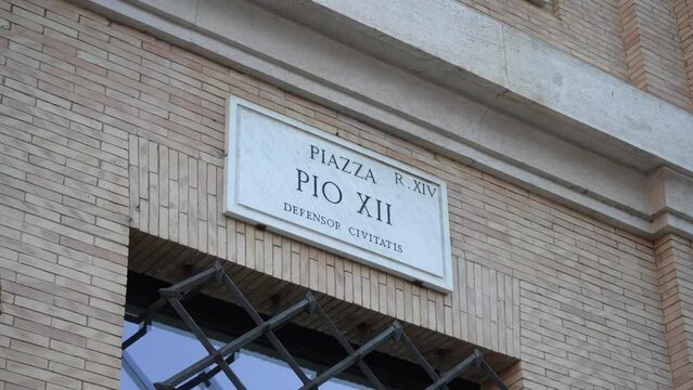 Closeup of street name sign of Piazza Pio XII (Carrer Garbine) on wall of old house in Rome, Italy. Concept of vacations and travel. Shooting in slow motion.