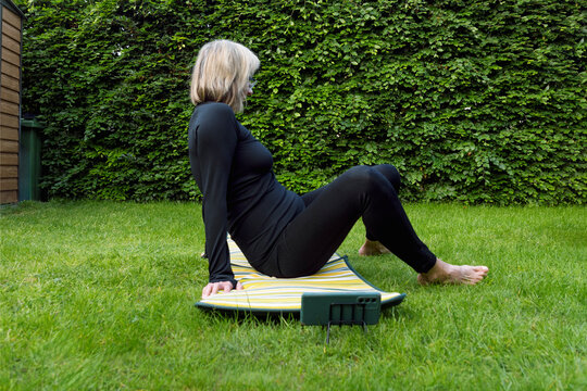 Young woman doing physical exercise outdoors in the garden at home