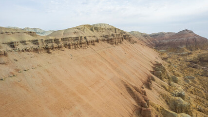 Colorful high mountains and a canyon made of clay. A large gorge with different rocks and different colors. Red, orange, white and yellow flowers of the walls of the rocks. A tourist walks. Aktau