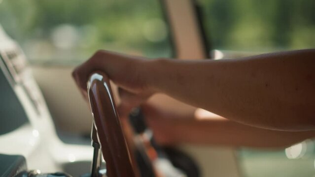 Captain turns helm driving modern yacht in control wheelhouse closeup. Man enjoys motor boat sailing at sea voyage. Skipper holds steering wheel in cabin