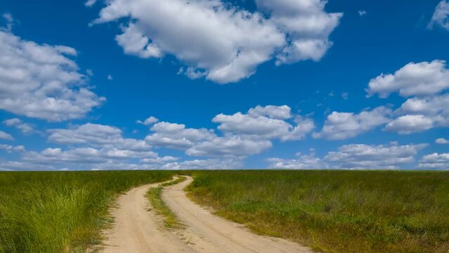 ground road among green prairie under cloudy sky time lapse scene