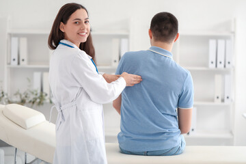 Fototapeta premium Female doctor checking posture of young man in clinic