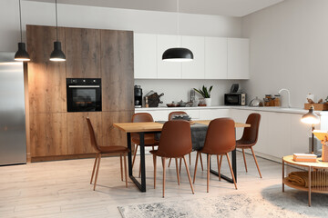 Interior of modern kitchen with dining table and glowing lamps