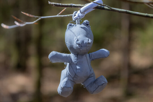 A tired dinosaur doll hangs in a tree