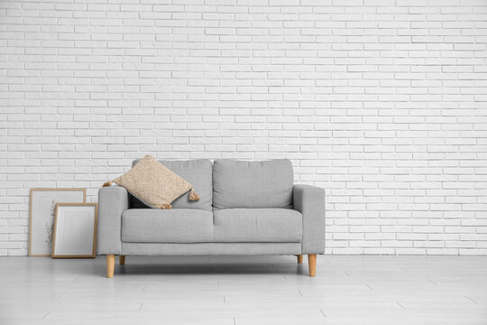 Interior of living room with sofa near white brick wall