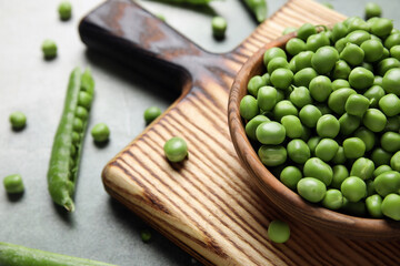 Bowl and wooden board with fresh green peas on grunge background