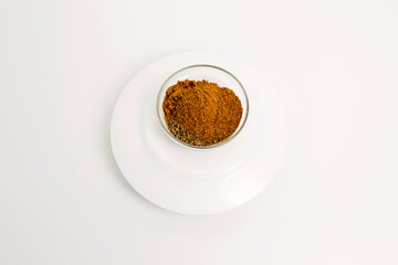 Homemade spice mixture in a glass plate on a white background.