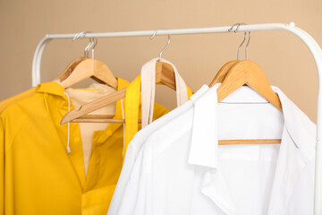 Rack with stylish clothes against color wall, closeup