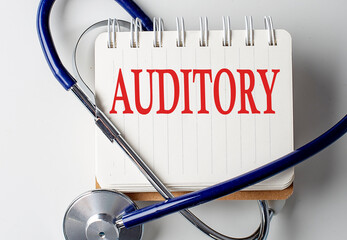 AUDITORY word on notebook with medical equipment on background