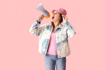 Young woman shouting into megaphone on pink background